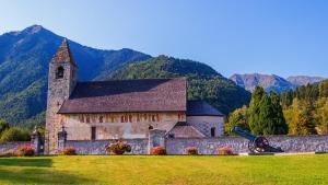 a large stone church with mountains in the background at Aria Life Hotel Pinzolo in Pinzolo