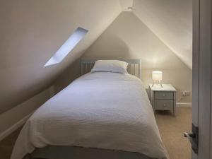 una camera da letto con letto bianco in mansarda di Wagglehead Cottage ad Aboyne