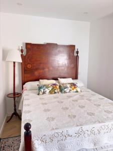 1 cama con cabecero de madera y manta blanca en Casa Milamores Constância, en Constância