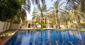 a large swimming pool with palm trees in front of a building at 2BR Downtown Dubai 5 Min Walk to Dubai Mall & Burj in Dubai
