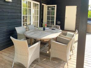a wooden table and chairs on a patio at Lovely Black Wooden House Near Tisvilde Hegn in Tisvilde +18 photos