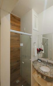 a bathroom with a sink and a glass shower at Hotel Porto de Paz - Shantiniketan in São Francisco do Sul