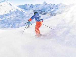 Due persone che sciano giù da una montagna innevata di Charmant studio montagnard avec accès bien-être, proche centre et pistes de ski au Grand-Bornand - FR-1-467-37 a Le Grand-Bornand