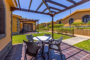 a patio with a table and chairs under a pergola at Maspalomas Resort by Dunas in Maspalomas