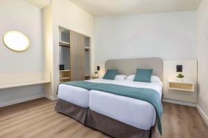 a bedroom with a large white bed with blue pillows at Maspalomas Resort by Dunas in Maspalomas