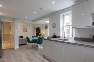 a kitchen with white cabinets and a table with green chairs at Sole Rose in Southwold