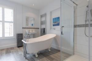 a white bathroom with a tub and a shower at Sole Rose in Southwold +22 photos