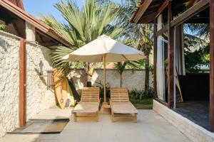 un patio con 2 sillas y una sombrilla en Ocean Bay Retreat, en Bingin Beach