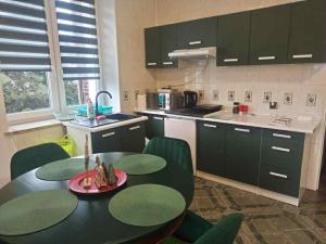 a kitchen with a black table and green chairs at Noclegi u Uli in Konin