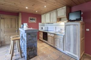a kitchen with wooden cabinets and a tv on the wall at Appartement à Megève in Megève +12 photos