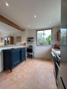 トゥルヴィル・シュル・メールにあるMaison Passifloraの青いキャビネットと窓付きの広いキッチン