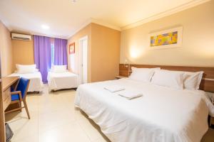a hotel room with two beds and a desk at Suíça Iguaçu Hotel & Resort in Foz do Iguaçu +79 photos