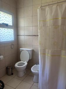 a bathroom with a toilet and a shower curtain at El Colibrí Casa de Campo in Villa María +33 photos