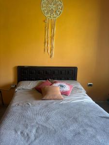 a bed with two pillows on it with a yellow wall at El Colibrí Casa de Campo in Villa María