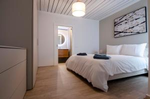 a white bedroom with a large bed and a television at Chic 2BR Apartment Steps from the Gzira Seafront in Il-Gżira