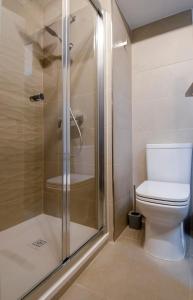 a bathroom with a toilet and a glass shower at Chic 2BR Apartment Steps from the Gzira Seafront in Il-Gżira +2 photos