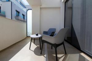 a white chair and a table in a room at Chic 2BR Apartment Steps from the Gzira Seafront in Il-Gżira