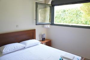 a bedroom with a white bed and a window at Ixia Beach in Ialyssos