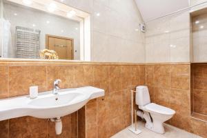 a bathroom with a sink and a toilet and a mirror at Saint John Two Bedroom Cottage by Reside Baltic in Vilnius