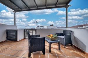 a patio with chairs and a table on a balcony at Apartamento El Charcon B - 10 meters to the Beach By Lanzarote Vacation Homes in Arrieta