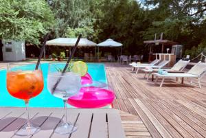 two wine glasses sitting on a table next to a swimming pool at Villa Meraville in Bologna