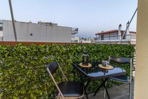 a table and chairs on a balcony with a hedge at Modern Loutraki Apartment 3min Walk to Beach Fits 4 in Loutraki