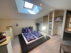 une chambre avec un lit avec des oreillers violets et une lucarne dans l'établissement Gite Lavande - Paradis de Provence, à Le Pin