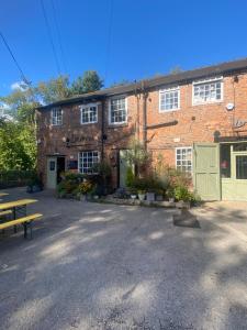 a brick building with a bench in front of it at Corner Cottage in Derby