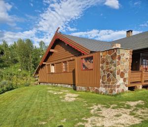 een blokhut met een stenen muur naast een tuin bij Springaren - cabin close to Gaustatoppen in Tuddal