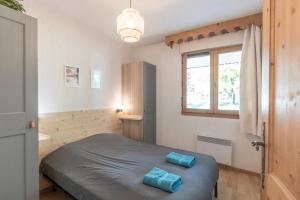 a bedroom with a bed with two blue pillows on it at Appartement à Samoëns – 6 couchages in Samoëns