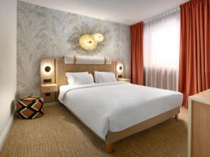 a bedroom with a large white bed and a window at Kyriad Prestige Hotel Clermont-Ferrand in Clermont-Ferrand +57 photos