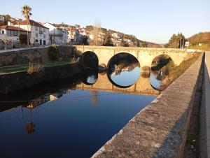 a bridge over a river with a reflection in the water at A Encantada in Alqueve
