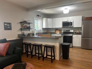 a kitchen with white cabinets and bar stools at Farmhouse by Ricketts Glen in Benton