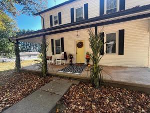 a white house with a yellow door and a patio at Farmhouse by Ricketts Glen in Benton