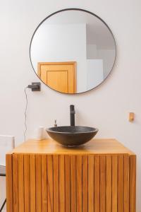 a black bowl sink on a wooden stand with a mirror at Lindo apartamento Porto - Gaia in Vila Nova de Gaia