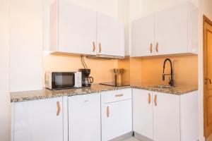 a kitchen with white cabinets and a microwave at Lindo apartamento Porto - Gaia in Vila Nova de Gaia +1 photo
