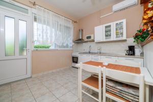 a kitchen with white cabinets and a table and a window at Apartments Mig in Supetarska Draga