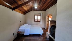 a bedroom with a bed in a room with a fireplace at Chalé Vista Pedra Partida in Monte Verde