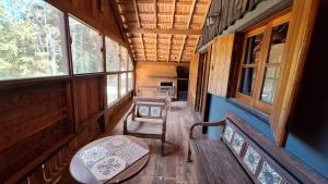 an inside view of a cabin with a bench and windows at Chalé Vista Pedra Partida in Monte Verde +16 photos