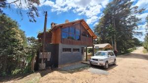 a house with a car parked in front of it at Chalé Vista Pedra Partida in Monte Verde