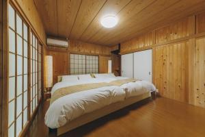 a large bed in a room with wooden walls at ItsumoYuki in Atami