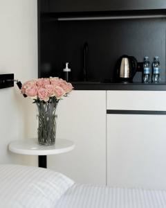 a vase of pink roses on a table in a kitchen at Ultramarinn Hotel in Odesa