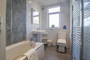 a bathroom with a tub and a toilet and a sink at Ashgrove House - 3 bedroom in Coatbridge +26 photos