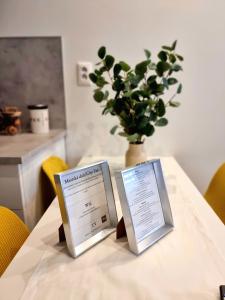 two signs on a table with a vase of plants at Apartment Banska - City Centre & Private Parking in Banská Bystrica