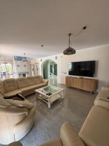 a living room with couches and a flat screen tv at Gorgeous Golf Villa Heated Pool Sea view in Adeje