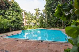 アーポラにあるSpacious 1BHK WiFi Balcony and Pool View near Anjunaの木々のあるリゾートの空のプール