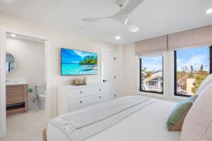 a white bedroom with a bed and a tv on the wall at Siesta Beachfront Paradise in Siesta Key +56 photos