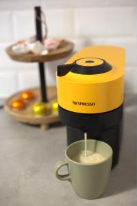a coffee maker is making a cup of coffee at Studio na Średniej - Gliwice Old Town Studio Flat in Gliwice +4 photos
