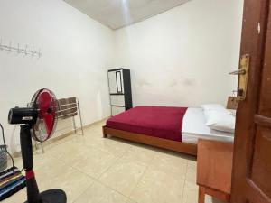 a room with a bed with a red blanket and a camera at Ijen adventure house in Ketapang