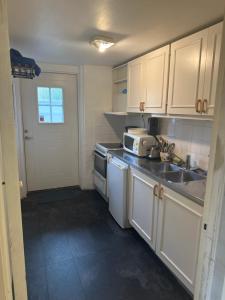 a kitchen with white cabinets and a sink and a microwave at Vittsjö charmiga hus in Vittsjö +18 photos